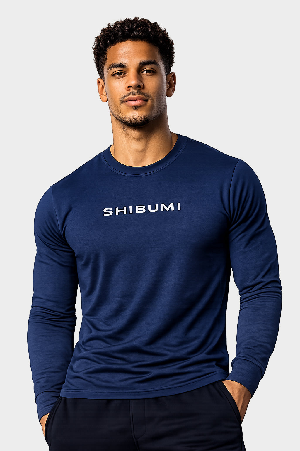 Man wearing a blue long-sleeve shirt with 'SHIBUMI' logo on a light gray background